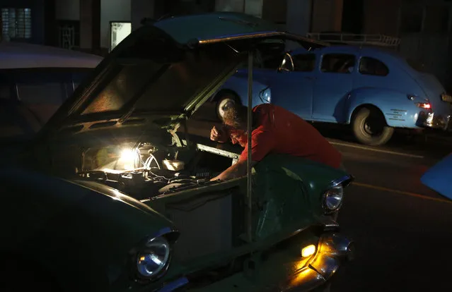 In this December 20, 2014 photo, a taxi driver repairs his vintage American car in Havana, Cuba. U.S. car sales have been banned in Cuba since 1959. Cubans have been have been forced to patch together Fords, Chevrolets and Chryslers that date back to before Fidel Castro's revolution which can make it appear like the country is stuck in a 1950s time warp. (Photo by Desmond Boylan/AP Photo)