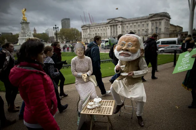 Supporters of the global civic campaign group Avaaz wear masks representing Indian Prime Minister Narendra Modi and Britain's Queen Elizabeth II as they pose for the media to highlight the decisions Modi can make on climate change policy and financing ahead of the upcoming G20 summit and Paris climate talks, outside Buckingham Palace in London, Friday, November 13, 2015. (Photo by Matt Dunham/AP Photo)