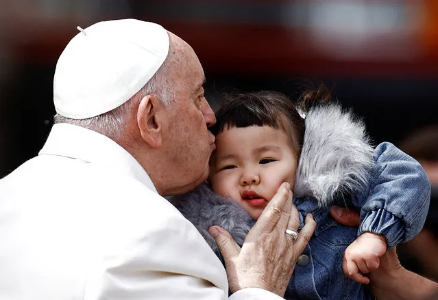 Pope Francis kisses a child during the weekly general audience in St. Peter's Square at the Vatican on March 29, 2023. (Photo by Guglielmo Mangiapane/Reuters)