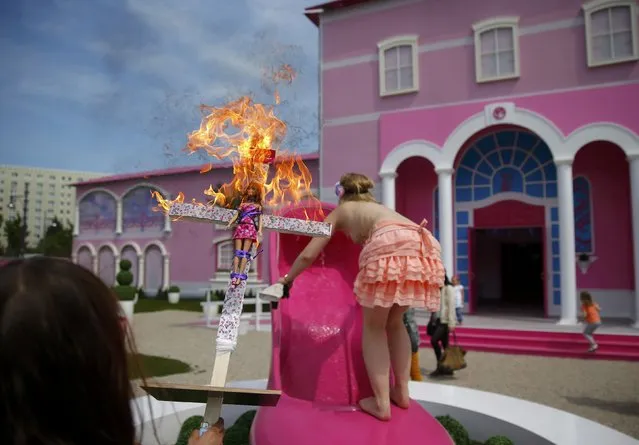 Activists from women's rights group Femen burn a barbie doll on a cross as they protest outside a “Barbie Dreamhouse” of Mattel's Barbie dolls in Berlin, May 16, 2013. (Photo by Pawel Kopczynski/Reuters)