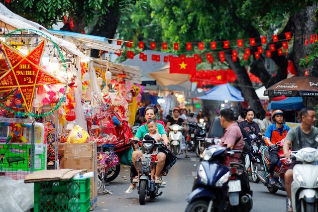 People ride motorbikes past shops selling decorations for the Mid-Autumn Festival at a street in Hanoi, Vietnam, 06 October 2025. The Mid-Autumn Festival, also known as Tet Trung Thu in Vietnam, is celebrated on the 15th day of the eighth lunar month and falls on 06 October this year. (Photo by Luong Thai Linh/EPA)