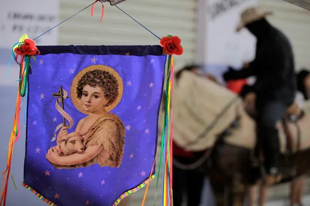 A banner of St John the Baptist hangs from the storefront of an artisan shop in Pirenopolis, Brazil, during the annual “Cavalhadas” festival, Sunday, May 19, 2013. The popular festival, featuring masked horsemen, is a tradition that was introduced in the 1800's by a Portuguese priest to mark the the ascension of Christ. The 3-day festival reenacts the Christian knights' medieval defeat of the Moors. (Photo by Eraldo Peres/AP Photo)