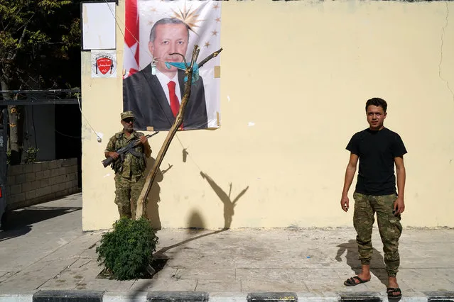 Members of Turkish-backed Free Syrian Army (FSA) stand in front of a wall where a portrait of Turkish President Tayyip Erdogan is displayed in the border town of Jarablus, Syria, October 19, 2016. (Photo by Umit Bektas/Reuters)