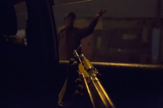 A police officer points an AK-47 assault rifle towards a man being questioned on a street from the inside of an unmarked vehicle during a night patrol in Nairobi, Kenya, October 30, 2015. (Photo by Siegfried Modola/Reuters)