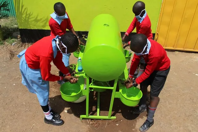 Pupils wash their hands at water points to control spread of coronavirus on the first day of official school opening at Precious Talent Top School, Kenya's capital Nairobi on Monday, January 4, 2021, as schools re-opened after a nine month break due to the COVID-19 pandemic. All primary and secondary schools in the country were reopened in congested classes despite efforts by the national government to have fulfilled their promises of having new desks and new classes to avoid the social distance calamity which could cause the spread of the pandemic in schools. (Photo by AP Photo/Stringer)