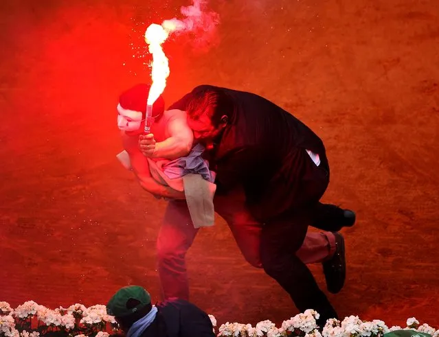 A security guard restrains a protester after he lit a flare and ran on the court before the start of a game in the men's singles final match between Rafael Nadal and David Ferrer at the French Open in Paris, on June 9, 2013. (Photo by Julian Finney/Getty Images)