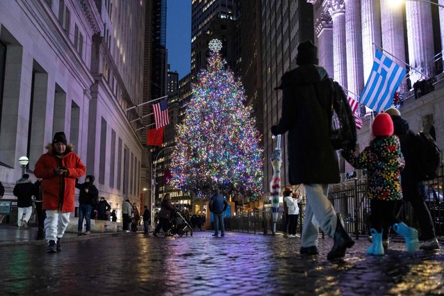 People walk past a Christmas tree outside the New York Stock Exchange, Wednesday, December 10, 2025, in New York. (Photo by Yuki Iwamura/AP Photo)