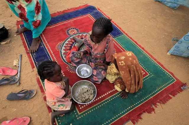 Sudanese refugee children who have fled the violence in Sudan's Darfur region eat their breakfast beside makeshift shelters near the border between Sudan and Chad in Koufroun, Chad on May 11, 2023. (Photo by Zohra Bensemra/Reuters)