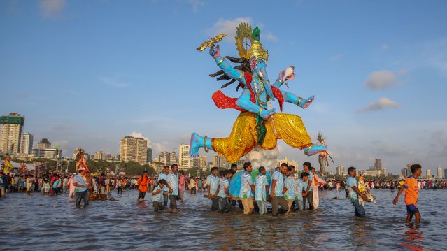 Hindu devotees carry the idol of Lord Ganesh, deity of prosperity,for immersion off the coast of Arabian sea on the last day of Ganesh Chaturthi festival on September 17, 2024 in Mumbai, India. Mumbai celebrates Ganesh Chaturthi with immense fervor, transforming the city into a vibrant hub of devotion and cultural expression. The festival, which lasts for ten days, culminates in grand processions where millions gather to bid farewell to the beloved elephant-headed deity, Ganesha, with chants of “Ganpati Bappa Morya!” echoing through the streets as idols are immersed in the Arabian Sea. (Photo by Ritesh Shukla/Getty Images)