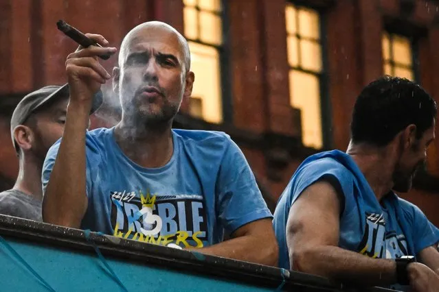 Manchester City's Spanish manager Pep Guardiola smokes a cigar as he celebrates with his players during an open-top bus victory parade in the streets of Manchester, northern England on June 12, 2023, as they celebrate with the European Cup, the FA Cup and the Premier League trophies. Manchester City tasted Champions League glory at last on Saturday as a second-half Rodri strike gave the favourites a 1-0 victory over Inter Milan in a tense final, allowing Pep Guardiola's side to complete a remarkable treble. Having already claimed a fifth Premier League title in six seasons, and added the FA Cup, City are the first English club to win such a treble since Manchester United in 1999. (Photo by Paul Ellis/AFP Photo)