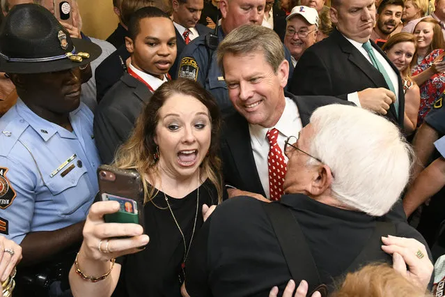 Georgia Republican gubernatorial candidate Brian Kemp, center, stops for a selfie with someone as he makes his way through a crowd of supporters after giving a victory speech during an election night party, Tuesday, July 24, 2018, in Athens, Ga. (Photo by John Amis/AP Photo)