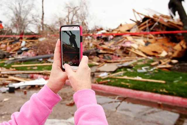 A former resident of the Landmark at the Lake Village West apartment complex takes photographs of tornado damage in Garland, Texas, December 28, 2015. In Texas, at least 11 people were killed in the Dallas area over the weekend by tornadoes, including one packing winds of up to 200 miles per hour (322 km per hour). The twister hit the city of Garland, killing eight people and blowing vehicles off highways. (Photo by Todd Yates/Reuters)