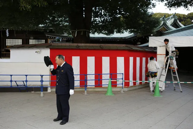 A shrine security official takes off his hat as workers fix decorations ahead of New Year celebrations at the Meiji Shrine in Tokyo, Japan, December 31, 2015. (Photo by Thomas Peter/Reuters)