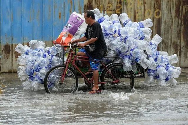 A man uses his pedicab to transport used plastic containers along a flooded street in Valenzuela city, Philippines on, Wednesday, August 2, 2023. Rains have continued to pour after two consecutive typhoons passed the country causing floods in some cities and provinces. (Photo by Aaron Favila/AP Photo)
