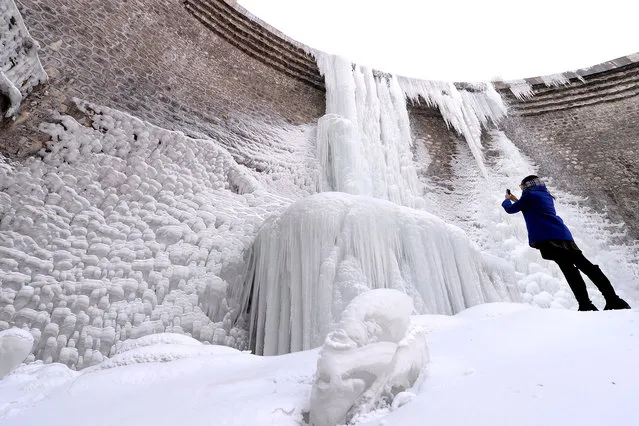 A tourist takes photos of a frozen waterfall in Rizhao city, east China's Shandong province, 19 January 2016. Most parts of China will experience a rapid drop in temperatures along with snow and rain in the coming days as a strong cold front is on the way, and will disrupt travel for the upcoming Spring Festival, which falls on Feb. 8 this year. The National Meteorological Center said temperatures will drop sharply in northwestern, northern and northeastern China, with temperatures in some areas down by up to 14 degrees Celsius. (Photo by Imaginechina/Splash News)