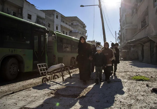 Syrians gather during an evacuation operation of rebel fighters and their families from rebel-held neighbourhoods on December 15, 2016 in the embattled city of Aleppo. A convoy of ambulances and buses left rebel territory in Aleppo in the first evacuations under a deal for opposition fighters to leave the city after years of fighting. The rebel withdrawal will pave the way for President Bashar al-Assad's forces to reclaim complete control of Syria's second city, handing the regime its biggest victory in more than five years of civil war. (Photo by Karam Al-Masri/AFP Photo)