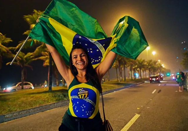 A supporter of Brazilian presidential candidate for the Social Liberal Party (PSL) Jair Bolsonaro celebrates outside his home in Rio de Janeiro, Brazil on October 7, 2018, during general elections. Polarizing far- right politician Jair Bolsonaro was the big winner of a first- round presidential election in Brazil on Sunday, according to virtually complete results – but a final victory in a run- off to be held in three weeks is far from assured. (Photo by Carl De Souza/AFP Photo)
