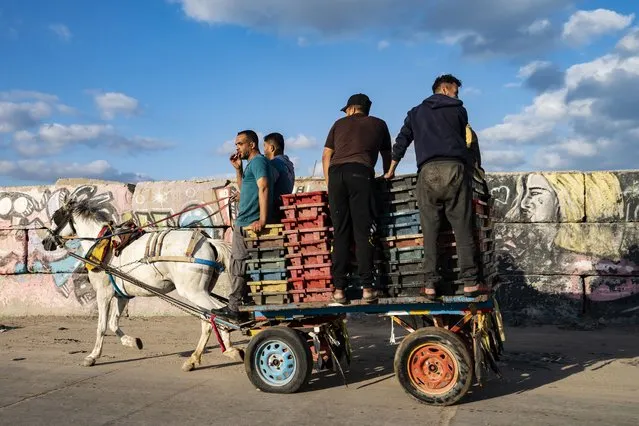 A fisherman takes a drag of a cigarette as the day's haul is delivered to market by horse-drawn cart after a limited number of boats were allowed to return to the sea following a cease-fire reached after an 11-day war between Hamas and Israel, in Gaza City, Sunday, May 23, 2021. (Photo by John Minchillo/AP Photo)