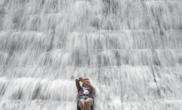A woman enjoys the water overflowing from a defunct but still watery reservoir called the Wawa dam in Montalban in Manila on March 22, 2015. The Philippines observes World Water day on March 22, a global event that focuses on finding access to clean and safe water. (Photo by Noel Celisnoel/AFP Photo)