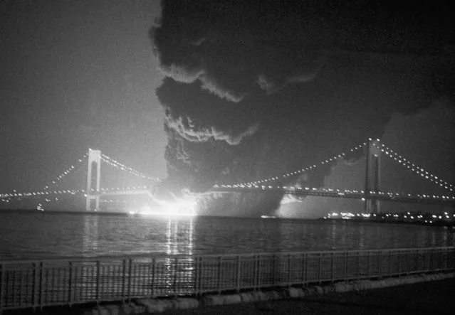 Smoke rises from a collision between the U.S. container ship Sea Witch and the ESSO Brussels, in New York harbor near the Verrazano bridge in New York, June 2, 1973. The Sea Witch continues to smolder and list more than 20 degrees as fireboats and tugs continue emergency operations. (Photo by AP Photo)