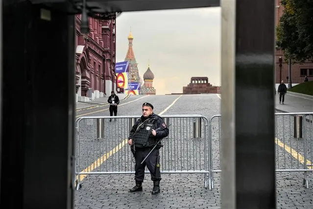 A policeman stands in front of barriers that block access to Red Square with the St. Basil's Cathedral and Lenin Mausoleum in the background ahead of a planned concert in Moscow, Russia, Thursday, September 29, 2022. The Kremlin said that Russian President Vladimir Putin and the leaders of the four regions of Ukraine that held a referendum on joining Russia will attend a ceremony to sign documents on the regions' incorporation into Russia, which will be followed by a big concert on Red Square. (Photo by Alexander Zemlianichenko/AP Photo)