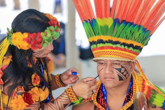 An environmental activist from Brazil wearing a traditional outfit has his face painted at the COP28 United Nations climate summit in Dubai on December 3, 2023. (Photo by Karim Sahib/AFP Photo)