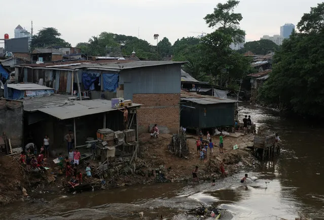 People gather near their houses at a slum area at the Ciliwung river bank at Jatinegara district in Jakarta, Indonesia, December 29, 2016. (Photo by Reuters/Beawiharta)