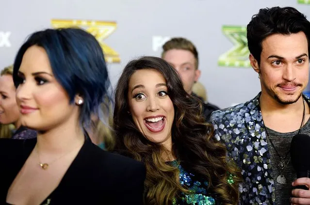Sierra Deaton (center) photobombs judge Demi Lovato's interview as Alex Kinsey speaks to a television reporter backstage after the folk duo won “The X Factor” in Los Angeles, on December 19, 2013. Winners Kinsey and Deaton won a $1 million recording contract with Sony Music Entertainment. (Photo by Kevork Djansezian/Reuters)