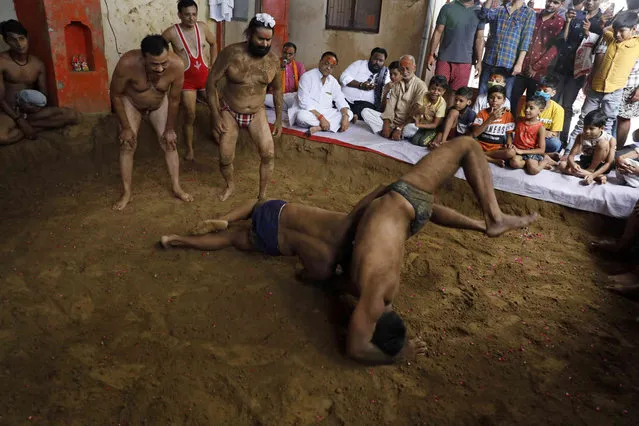 Traditional Indian wrestlers engage in a bout during Nag Panchami festival in Prayagraj, India. Friday, August 13, 2021. Every year, the wrestlers offer prayers and hold bouts to mark the festival which is primarily dedicated to the worship of snakes. (Photo by Rajesh Kumar Singh/AP Photo)