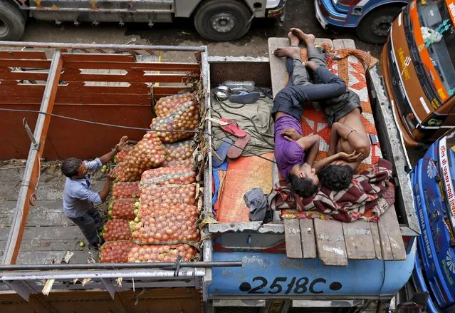 A worker unloads sacks of vegetables as men sleep on top of a truck at a wholesale vegetable market in the western Indian city of Ahmedabad in this July 14, 2014 file photo. (Photo by Amit Dave/Reuters)