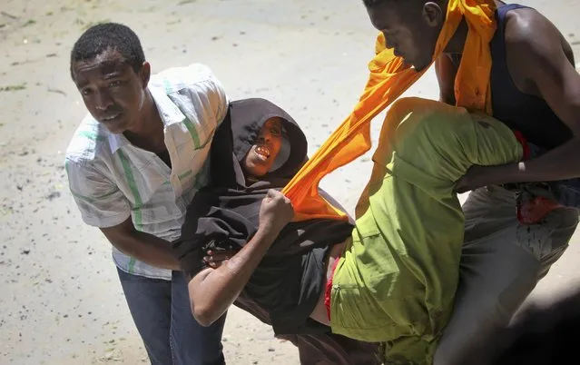 A person is assisted after being wounded when a car bomb detonated at the gates of a government office complex in the capital Mogadishu, Somalia Tuesday, April 14, 2015. (Photo by Farah Abdi Warsameh/AP Photo)