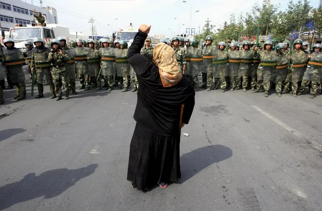 A local woman on a crutch shouts at Chinese paramilitary police wearing riot gear as a crowd of angry locals confront security forces on a street in the city of Urumqi in China's Xinjiang Autonomous Region, in this July 7, 2009 file photo. (Photo by David Gray/Reuters)