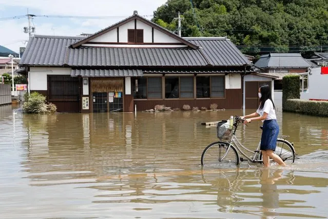 A woman pushes a bicycle through a flooded street in Takeo, Saga Prefecture, western Japan, August 15, 2021. (Photo by Kim Kyung-Hoon/Reuters)