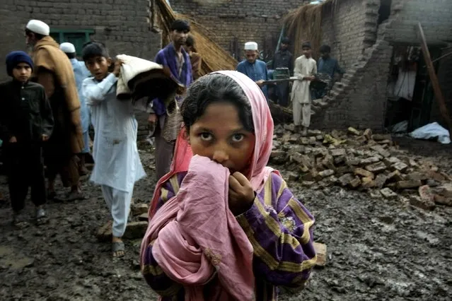 People salvage what they can from a house that collapsed from heavy rain and windstorm that reached up to a speed of 120 kph (75 mph) Sunday evening which collapsed hundreds of buildings, uprooted trees, and electric poles, in Peshawar, Pakistan, Monday, April 27, 2015. (Photo by Mohammad Sajjad/AP Photo)