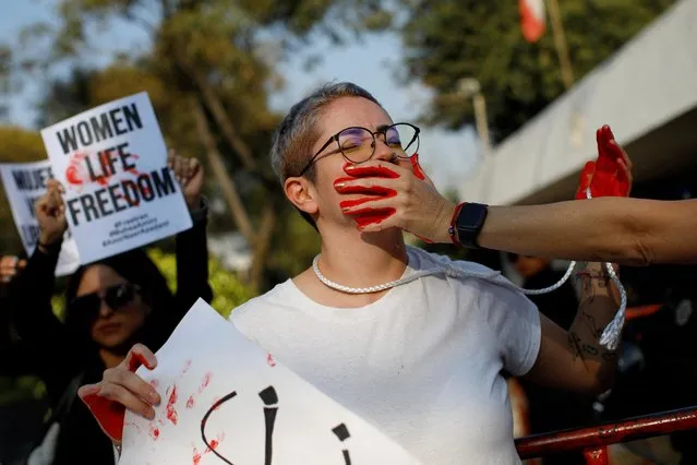 A woman has her mouth painted in red during a protest against Iran's ruling theocracy following the death of young Kurdish Iranian woman Mahsa Amini demanding authorities to free thousands of detained protesters and to stop executions, outside Iran's embassy, in Mexico City, Mexico on December 19, 2022. (Photo by Raquel Cunha/Reuters)