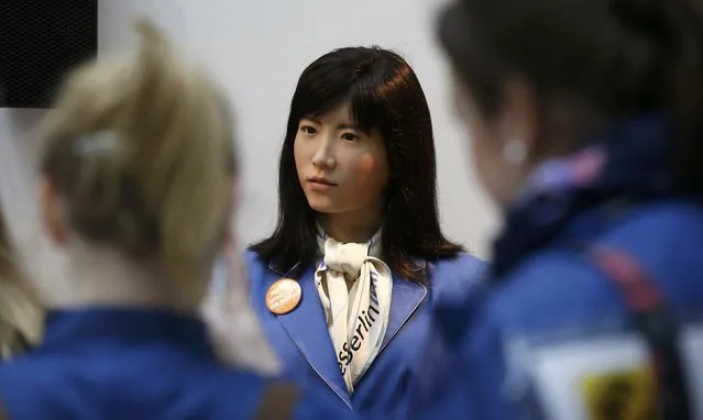 Visitors listen to communication android “Chihira Kanae” (C) at an information counter at the International Tourism Trade Fair (ITB) in Berlin, Germany, March 9, 2016. “Chihira Kanae”, which was created by Toshiba, has her own information counter where she welcomes visitors through two way communication, provides information on the trade fair and answers any questions visitors may have in English, German, Japanese and Chinese. (Photo by Fabrizio Bensch/Reuters)