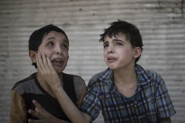 In this Saturday, June 24, 2017 file photo, Zeid Ali, 12, left, and Hodayfa Ali, 11, comfort each other after their house was hit and collapsed during fighting between Iraqi forces and Islamic State militants in Mosul, Iraq. The Ali cousins said some of their family members are still under the rubble. (Photo by Felipe Dana/AP Photo/File)