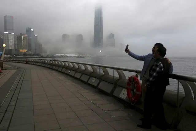 People take a selfie in front of the financial Central district under foggy weather in Hong Kong, China March 9, 2016. (Photo by Bobby Yip/Reuters)