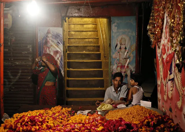 Boys sit at a stall selling flowers next to a roadside temple in the old quarters of Delhi August 7, 2014. (Photo by Anindito Mukherjee/Reuters)