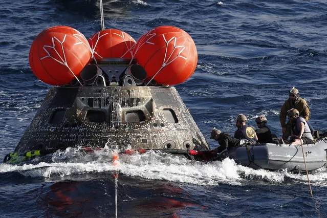 U.S. Navy divers attach winch cables to NASA's Orion capsule after being successfully secured by a NASA and U.S. Navy team, off the coast of Baja California, Mexico, 11 December 2022. The Orion capsule returns back to earth after a 25.5-day mission obiting the moon and back to Earth in a recovery operation involving the US Navy and NASA. (Photo by Caroline Brehman/EPA/EFE)