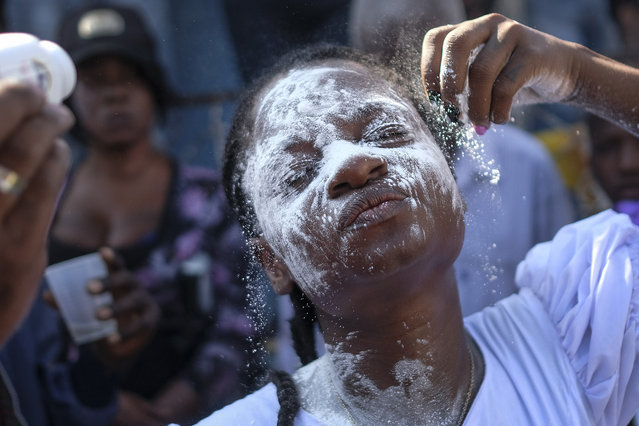 A person believed to be possessed with the Gede spirit is doused with while powder during a ceremony honoring the Haitian Vodou spirit of Baron Samedi and Gede at the National Cemetery in Port-au-Prince, Haiti, Monday, November 1, 2021. (Photo by Matias Delacroix/AP Photo)