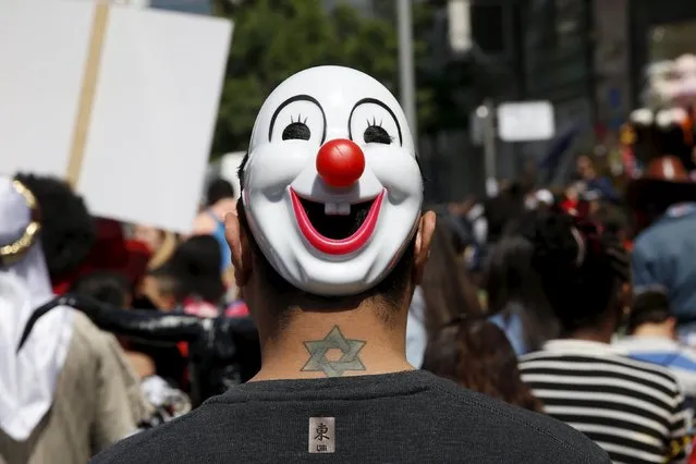 A man wearing a mask takes part in a parade marking the upcoming Jewish holiday of Purim outside the Bialik Rogozin school in Tel Aviv, Israel March 22, 2016. At Bialik Rogozin, children of migrant workers and refugees are educated alongside native Israelis. Purim is a celebration of the Jews' salvation from genocide in ancient Persia, as recounted in the Book of Esther. (Photo by Baz Ratner/Reuters)