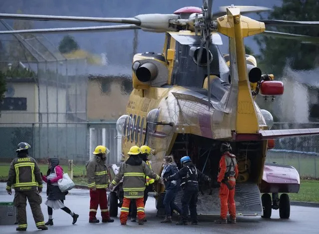 Search and rescue personnel help flood evacuees disembark from a helicopter in Agassiz, British Columbia, Monday, November 15, 2021. (Photo by Jonathan Hayward/The Canadian Press via AP Photo)