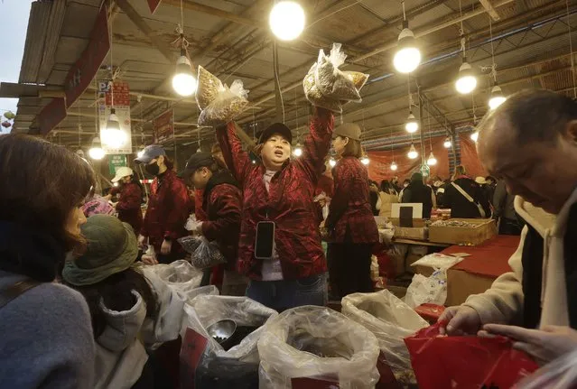 A sales woman shouts at the customers to buy as they go shopping for the upcoming Lunar New Year celebrations at the Dihua street market in Taipei, Taiwan, Thursday, February 8, 2024. (Photo by Chiang Ying-ying/AP Photo)