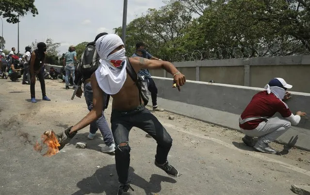 An anti-government protester launches a molotov cocktail at National Guard forces outside La Carlota airbase during clashes between the two sides in Caracas, Venezuela, Wednesday, May 1, 2019. (Photo by Rodrigo Abd/AP Photo)