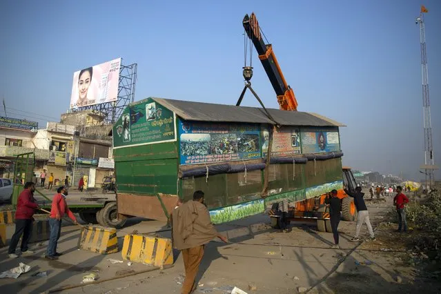 Indian farmers use a crane to lift a temporary structure used during protests as they start vacating the protest site in Singhu, on the outskirts of New Delhi, India, Saturday, December 11, 2021. Tens of thousands of jubilant Indian farmers on Saturday cleared protest sites on the capital’s outskirts and began returning home, marking an end to their year-long demonstrations against agricultural reforms that were repealed by Prime Minister Narendra Modi's government in a rare retreat. (Photo by Altaf Qadri/AP Photo)