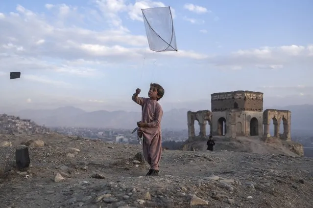 A boy flies a kite on Tape Nadir Khan hill in Kabul, Afghanistan, on Saturday, December 4 , 2021. (Photo by Petros Giannakouris/AP Photo)