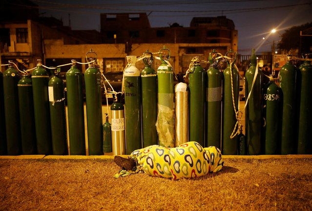 A person sleeps next to empty oxygen tanks to save a spot in the queue, as the supplier refills a tank per person and attends only up to 60 people a day, during the outbreak of the coronavirus disease (COVID-19), in Callao, Peru on February 4, 2021. (Photo by Sebastian Castaneda/Reuters)