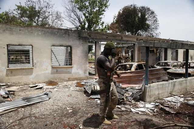 A soldier walks through a burnt building at the headquarters of Michika local government in Michika town, after the Nigerian military recaptured it from Boko Haram, in Adamawa state May 10, 2015. Boko Haram has said it wanted to revive the 19th century caliphate of Usman Dan Fodio, an Islamic scholar who threw off corrupt Hausa kings and established strict Sharia law. (Photo by Akintunde Akinleye/Reuters)