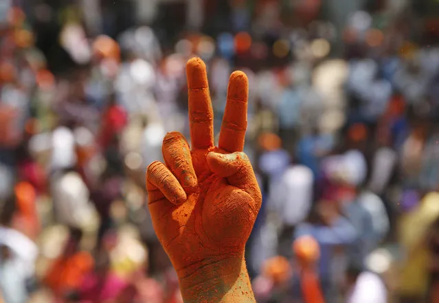 A Bharatiya Janata Party supporter's hands are covered in saffron color as he shows victory sign as they celebrate winning seats in the Uttar Pradesh state legislature elections in, Lucknow, India, Saturday, March 11, 2017. India's governing Hindu nationalist party was heading for major victories Saturday in key state legislature elections that are seen as a referendum on the performance of Prime Minister Narendra Modi's nearly 3-year-old government. (Photo by Rajesh Kumar Singh/AP Photo)